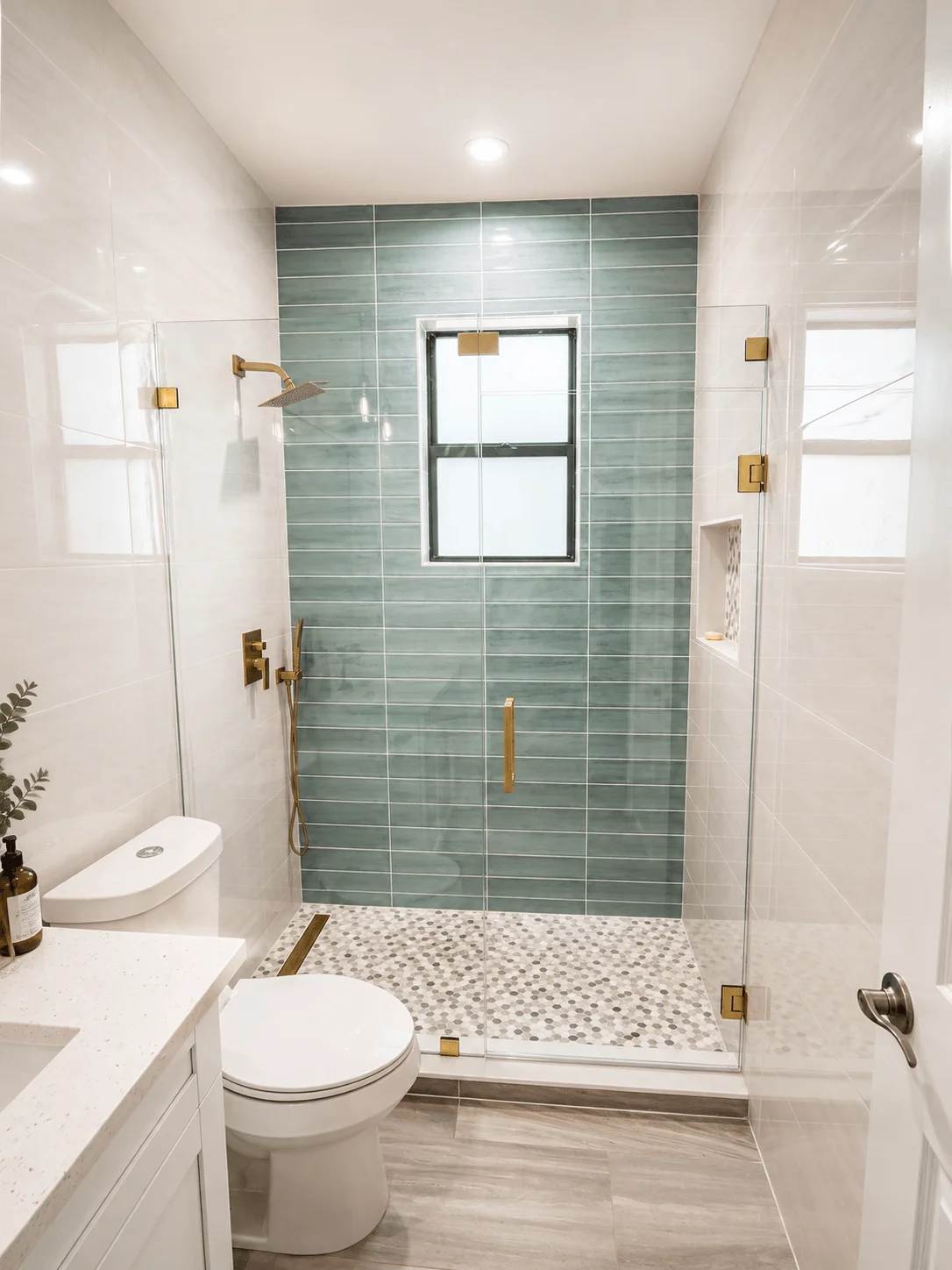 Modern bathroom remodel with green tile shower, glass enclosure, and gold fixtures